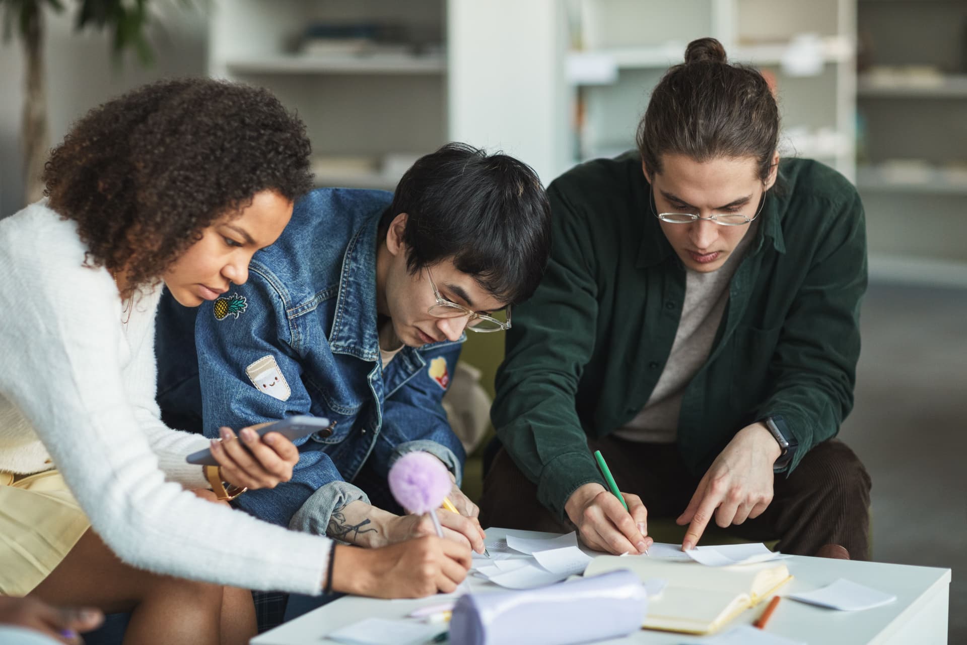 A small group of classmates working together at a table with notebooks