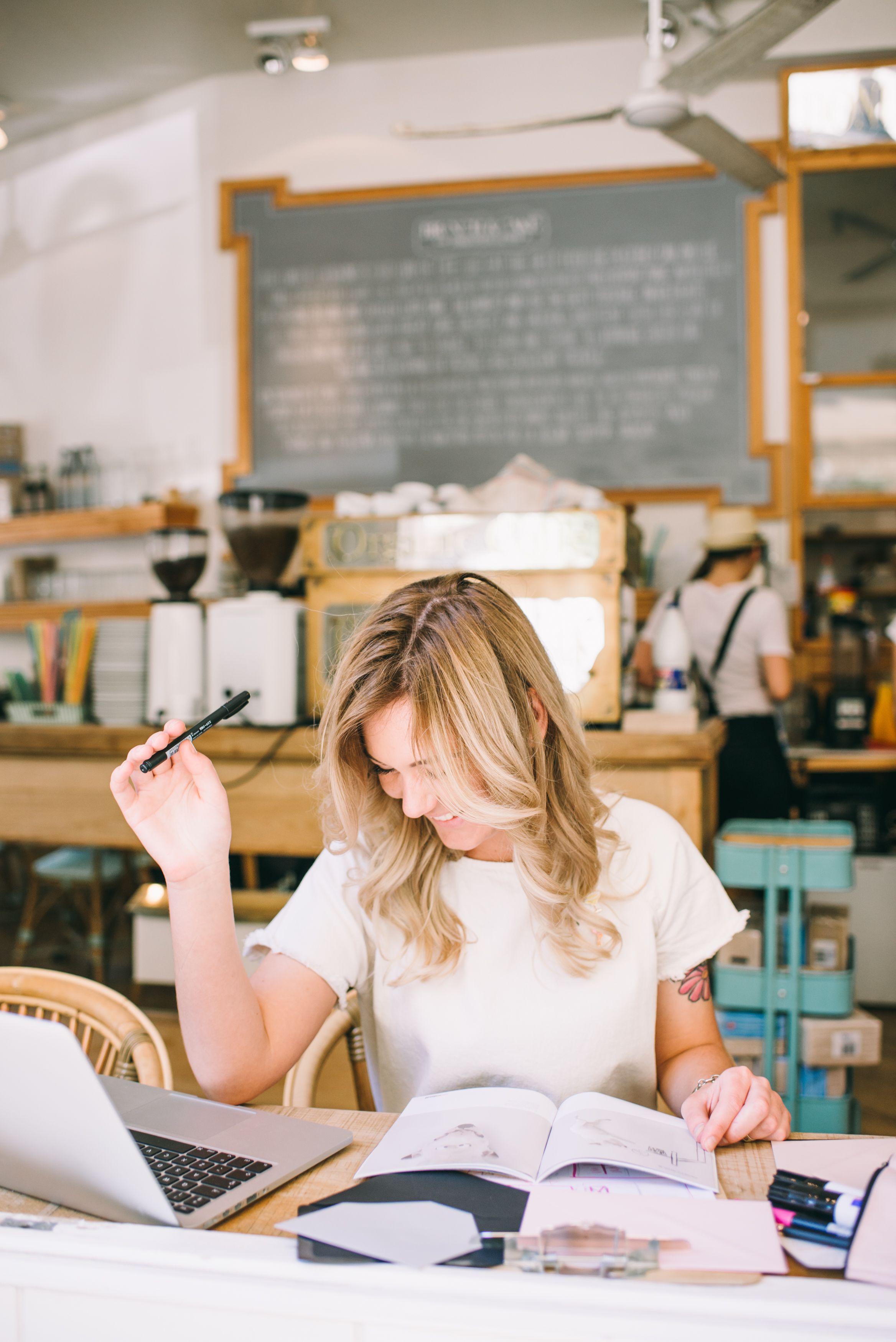 A woman working on a laptop at a table in a cafe